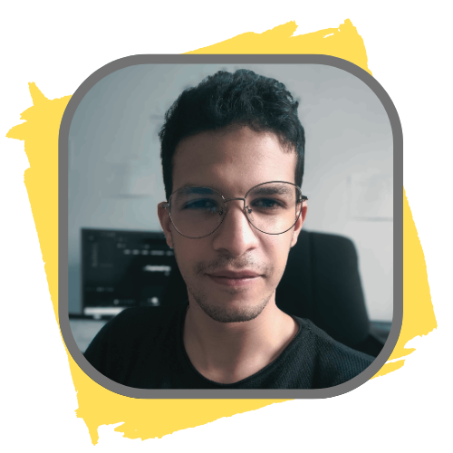 Portrait of Mohamed Gasmi, also known as Med Gasmi, a young man with short dark hair and round glasses, looking directly at the camera. He is seated in a modern workspace with a computer in the background. The image has a square frame with rounded corners and is set against a yellow background with a brushstroke border.